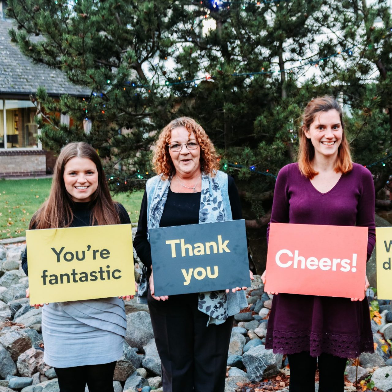 Four staff holding boards saying thank you