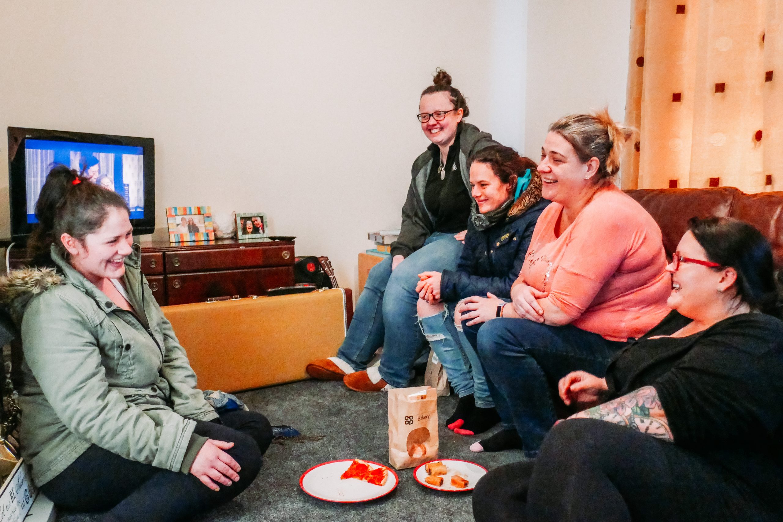 Amy and other women in a living room laughing and eating biscuits