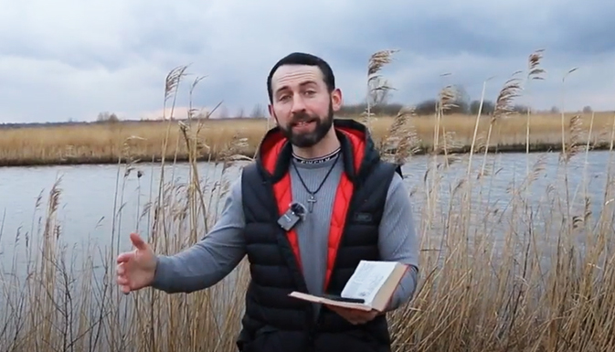Laurence standing next to a river talking with a Bible
