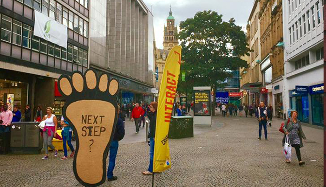 Sheffield City Centre with a big cardboard foot that says 'Next Step?' on it