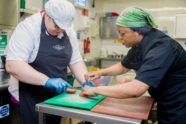 Aderemi teaching chopping skills in the Munch kitchen